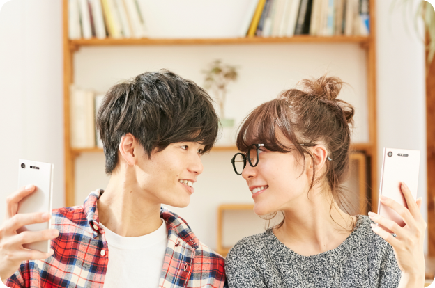 部屋でスマホを見ながら話す男女